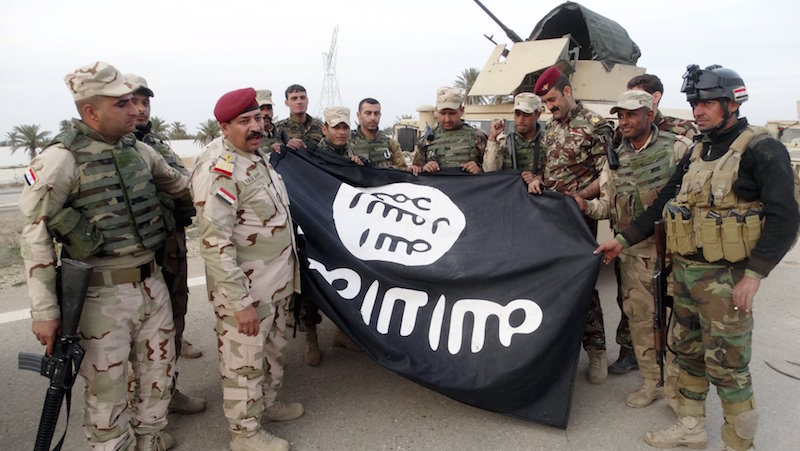 Iraqi security forces stand with an Islamic State flag which they pulled down in the city of Ramadi